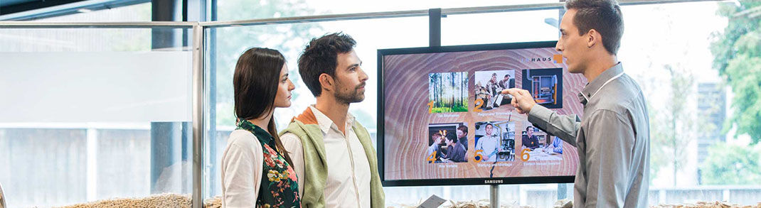 Drei Personen stehen vor einem Bildschirm und diskutieren über Bilder und Informationen, die darauf angezeigt werden. Drei Personen stehen vor einem Bildschirm und diskutieren über Bilder und Informationen, die darauf angezeigt werden.