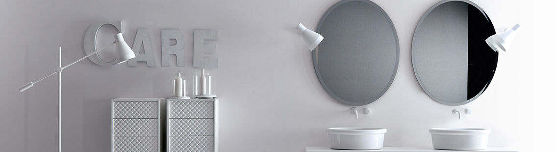 Zeitgenössisches Badezimmer in Weiß mit zwei ovalen Spiegeln, Doppelwaschbecken und stilvollen Lampen. Minimalistische Einrichtung mit skulpturalen Details. Zeitgenössisches Badezimmer in Weiß mit zwei ovalen Spiegeln, Doppelwaschbecken und stilvollen Lampen. Minimalistische Einrichtung mit skulpturalen Details.