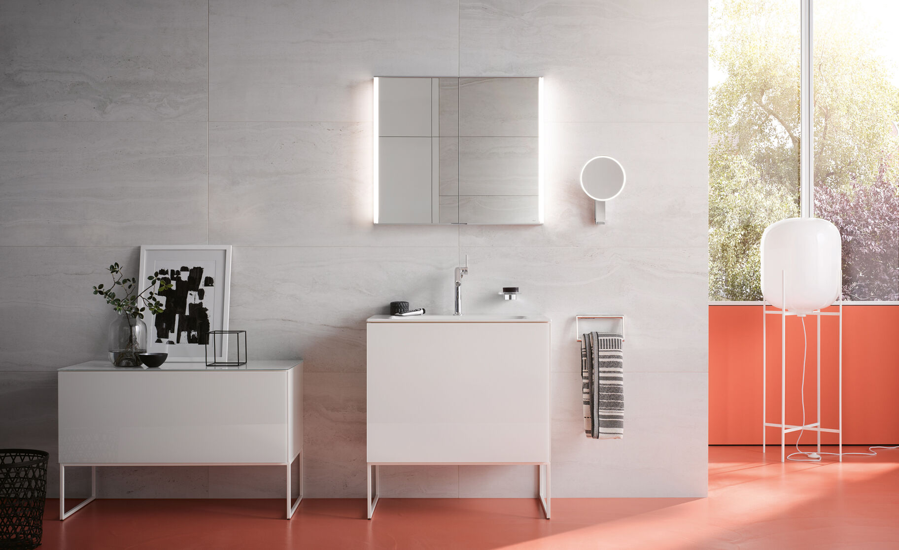 Modernes Badezimmer mit weißem Waschtisch, beleuchtetem Spiegel und rotem Boden. Großes Fenster bietet viel Licht; dekorative Pflanzen und Kunstwerke. Modernes Badezimmer mit weißem Waschtisch, beleuchtetem Spiegel und rotem Boden. Großes Fenster bietet viel Licht; dekorative Pflanzen und Kunstwerke.