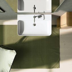 Modernes Badezimmer-Design von oben. Ein rechteckiges Waschbecken mit Spiegel, ein grüner Teppich und ein Holzschrank.