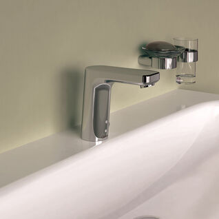Modernes Waschbecken mit chromfarbener Armatur. An der Wand befindet sich ein Seifenhalter und ein Glas. Schlichtes, elegantes Design. Modernes Waschbecken mit chromfarbener Armatur. An der Wand befindet sich ein Seifenhalter und ein Glas. Schlichtes, elegantes Design.