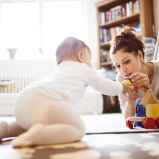 Eine Person spielt mit einem Baby auf dem Boden. Sie sind von Spielzeug umgeben, die Atmosphäre ist warm und gemütlich, perfekt für gemeinsame Momente. Eine Person spielt mit einem Baby auf dem Boden. Sie sind von Spielzeug umgeben, die Atmosphäre ist warm und gemütlich, perfekt für gemeinsame Momente.