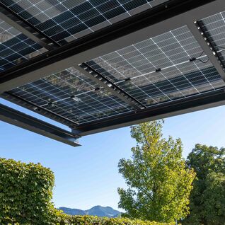 Nachhaltige &Uuml;berdachung aus Solarpanelen: Moderne Energiegewinnung trifft stilvolle Architektur in harmonischer, gr&uuml;ner Umgebung.