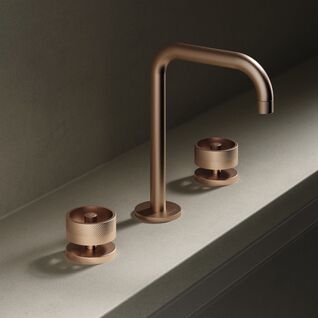 Kupferfarbene Armatur mit zwei Drehkn&ouml;pfen auf grauer Oberfl&auml;che. Elegantes, modernes Design in minimalistischer Umgebung.