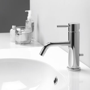 Ein stilvolles Waschbecken mit einer zylindrischen Chromarmatur. Auf der Ablagefläche stehen diverse Pflegeprodukte. Zeitloses und elegantes Design. Ein stilvolles Waschbecken mit einer zylindrischen Chromarmatur. Auf der Ablagefläche stehen diverse Pflegeprodukte. Zeitloses und elegantes Design.