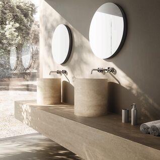 Modernes Badezimmer mit zwei runden Spiegeln und zylindrischen Waschbecken auf Holzplatte. Glaswand bietet Blick ins Freie f&uuml;r nat&uuml;rliche Helligkeit.