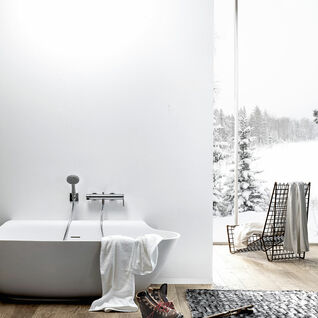 Ein modernes Badezimmer mit freistehender Badewanne und Blick auf verschneite Landschaft. Handtücher und Winterstiefel verleihen Gemütlichkeit. Ein modernes Badezimmer mit freistehender Badewanne und Blick auf verschneite Landschaft. Handtücher und Winterstiefel verleihen Gemütlichkeit.