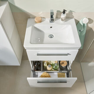 Weißes Badezimmerwaschbecken mit Stauraum darunter. Geöffnete Schublade zeigt organisierte Pflegeprodukte. Modern, hell und funktional gestaltet. Weißes Badezimmerwaschbecken mit Stauraum darunter. Geöffnete Schublade zeigt organisierte Pflegeprodukte. Modern, hell und funktional gestaltet.