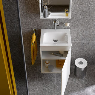 Kompaktes Badezimmer mit kleinem Waschbecken und Spiegelschrank. Gelbes Handtuch, offene Ablage mit Accessoires, graue Wandfliesen. Stilvoll und funktional. Kompaktes Badezimmer mit kleinem Waschbecken und Spiegelschrank. Gelbes Handtuch, offene Ablage mit Accessoires, graue Wandfliesen. Stilvoll und funktional.