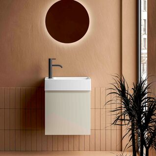 Modernes Badezimmer mit einem minimalistischen Waschbecken und einem runden, beleuchteten Spiegel. Die warmen Erdt&ouml;ne der W&auml;nde und der Bodenfliesen schaffen eine einladende Atmosph&auml;re.