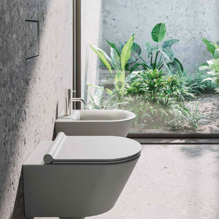 Modernes Badezimmer mit wandhängendem WC und Bidet. Große Glaswand mit Blick auf einen grünen Garten. Minimalistisches Design mit natürlichen Elementen. Modernes Badezimmer mit wandhängendem WC und Bidet. Große Glaswand mit Blick auf einen grünen Garten. Minimalistisches Design mit natürlichen Elementen.