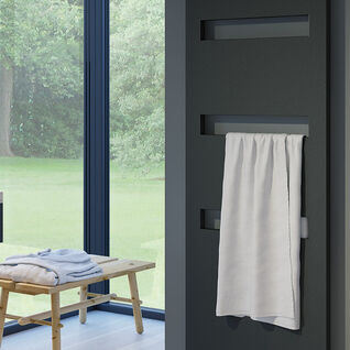 Schwarzer, moderner Heizkörper mit rechteckigen Öffnungen, daran hängt ein weißes Handtuch. Stilvoll und funktional in einem eleganten Raum. Schwarzer, moderner Heizkörper mit rechteckigen Öffnungen, daran hängt ein weißes Handtuch. Stilvoll und funktional in einem eleganten Raum.