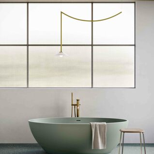 Ein modernes Bad mit freistehender gr&uuml;ner Wanne, goldenen Armaturen, gro&szlig;em Fenster, minimalistischer Lampe und Hocker mit Handtuch. Elegantes Design.