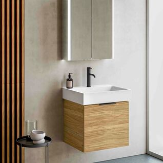 Elegantes Badezimmer mit einem h&ouml;lzernen Waschtisch, beleuchtetem Spiegelschrank und modernen Armaturen. Ein Beistelltisch erg&auml;nzt die minimalistische Einrichtung.
