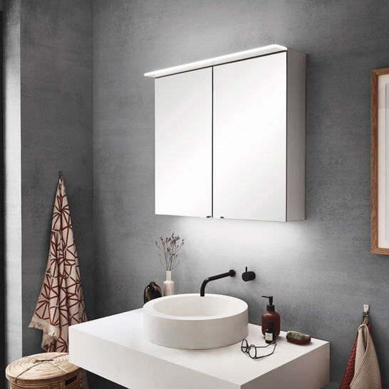 Modernes Badezimmer mit rundem Aufsatzwaschbecken, beleuchtetem Spiegelschrank und grauen Wänden. Ein großes Fenster bietet Stadtblick und viel Licht. Modernes Badezimmer mit rundem Aufsatzwaschbecken, beleuchtetem Spiegelschrank und grauen Wänden. Ein großes Fenster bietet Stadtblick und viel Licht.