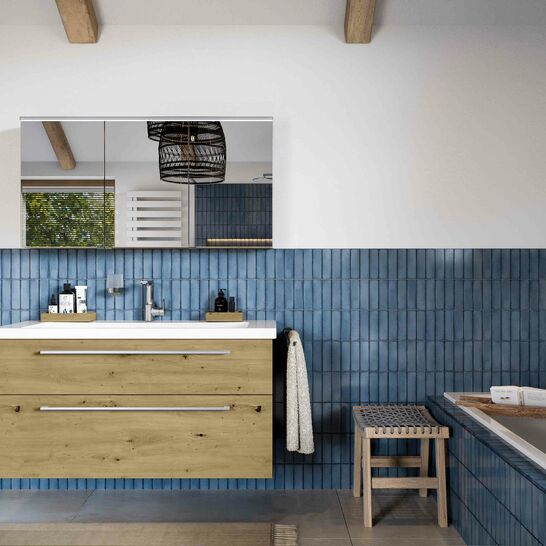 Modernes Badezimmer mit blauen Fliesen, Holzschr&auml;nken und freistehender Badewanne. Die Kombination aus Holz und Blau schafft ein warmes, einladendes Ambiente.