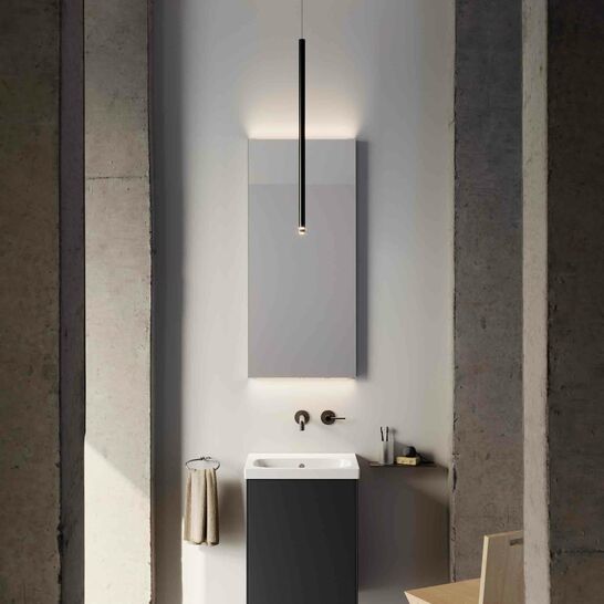 Modernes Badezimmer mit stilvollem Waschbecken, rechteckigem Spiegel und minimalistischer Beleuchtung. Dunkle Akzente und klare Linien dominieren den Raum.