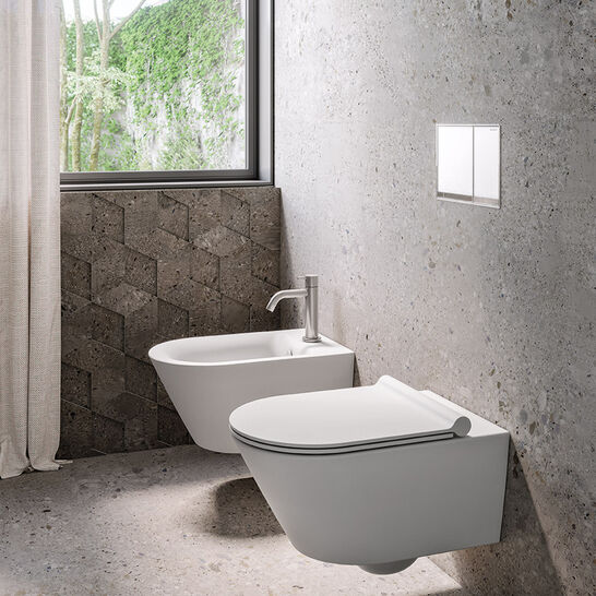 Modernes Badezimmer mit wandhängendem WC und Bidet, grauer Steinoptik und großem Fenster mit Blick ins Grüne. Schlichte Eleganz und natürliche Materialien.