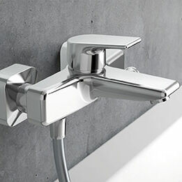 Moderne Wandarmatur aus Chrom mit rechteckigem Design, montiert an einer grauen Wand. Stilvoll und funktional für ein zeitgemäßes Badezimmer. Moderne Wandarmatur aus Chrom mit rechteckigem Design, montiert an einer grauen Wand. Stilvoll und funktional für ein zeitgemäßes Badezimmer.