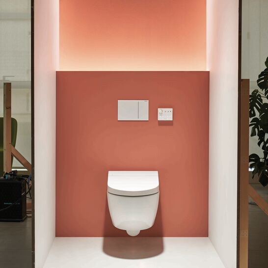 Modernes WC mit Wandmontage vor einer korallenroten Akzentwand, umgeben von sanfter Beleuchtung. Minimalistisches Design f&uuml;r ein stilvolles Badezimmer.