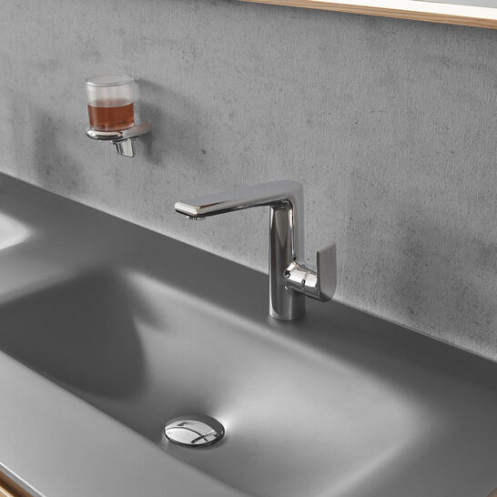 Modernes graues Waschbecken mit Chromarmatur vor einer Betonoptik-Wand. Glas für Zahnbürstenhalter montiert. Schlichtes, elegantes Design. Modernes graues Waschbecken mit Chromarmatur vor einer Betonoptik-Wand. Glas für Zahnbürstenhalter montiert. Schlichtes, elegantes Design.