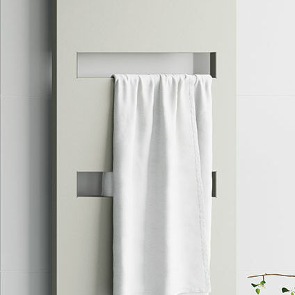 Moderner, weißer Heizkörper mit rechteckigen Ausschnitten, an dem ein weißes Handtuch hängt. Schlichtes Design vor einer weißen Wand mit einem kleinen Pflanzenakzent. Moderner, weißer Heizkörper mit rechteckigen Ausschnitten, an dem ein weißes Handtuch hängt. Schlichtes Design vor einer weißen Wand mit einem kleinen Pflanzenakzent.