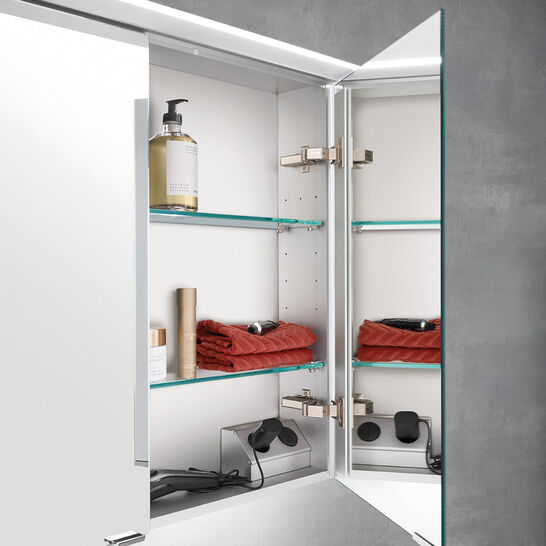 Nahaufnahme eines modernen Spiegelschranks mit Glasregalen. Enthält rote Handtücher, Pflegeprodukte und Accessoires, stilvoll und ordentlich arrangiert. Nahaufnahme eines modernen Spiegelschranks mit Glasregalen. Enthält rote Handtücher, Pflegeprodukte und Accessoires, stilvoll und ordentlich arrangiert.