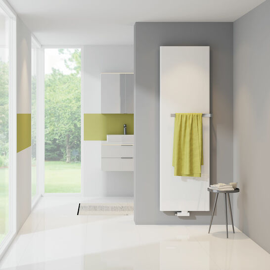 Schlichter, weißer Heizkörper an grauer Wand mit grünem Handtuch. Modernes Badezimmer-Design mit kleinem Tisch, der Handtücher hält. Frischer und eleganter Look. Schlichter, weißer Heizkörper an grauer Wand mit grünem Handtuch. Modernes Badezimmer-Design mit kleinem Tisch, der Handtücher hält. Frischer und eleganter Look.