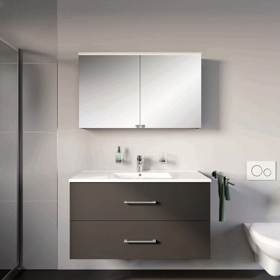 Modernes Badezimmer mit schwebendem dunkelgrauem Waschtisch und Spiegelschrank. Helle W&auml;nde und ein flauschiger, gr&uuml;ner Teppich sorgen f&uuml;r ein harmonisches Ambiente.