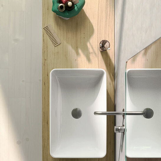 Ein minimalistisches Badezimmer-Design mit rechteckigem Waschbecken auf einer Holzplatte. Links liegen kleine Gegenstände und ein Kamm, daneben ein Spiegel.