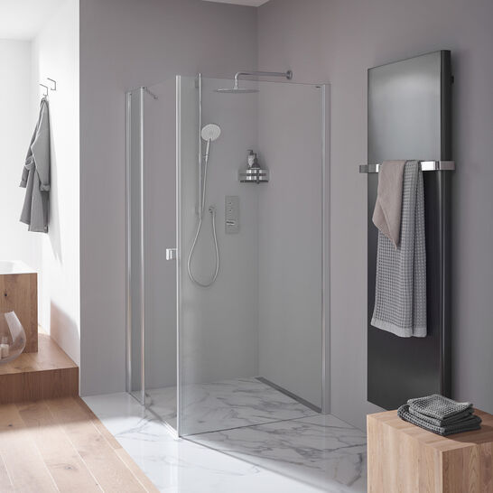 Eine moderne Dusche mit Glaswänden und Marmorfliesen. Ein schlichter Handtuchhalter mit Handtüchern daneben. Holz- und Grautöne dominieren das Design.
