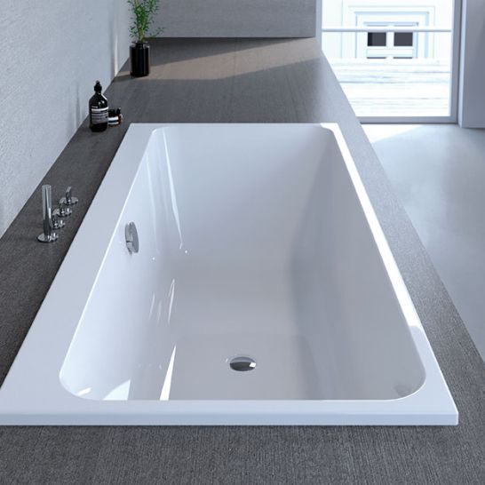 Gro&szlig;z&uuml;gige Einbaubadewanne mit rechteckigem Design, umgeben von einer grauen Ablagefl&auml;che. Modernes und minimalistisches Ambiente, ideal f&uuml;r ein stilvolles Badezimmer.
