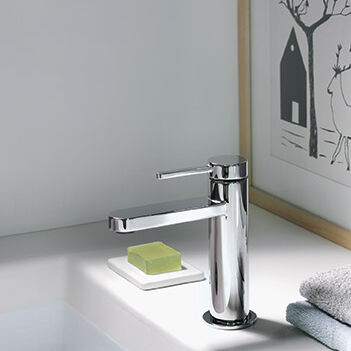 Ein elegantes Waschbecken mit moderner Chromarmatur. Seife auf Schale, gefaltete Handtücher, gerahmtes Bild im Hintergrund. Schlicht und stilvoll. Ein elegantes Waschbecken mit moderner Chromarmatur. Seife auf Schale, gefaltete Handtücher, gerahmtes Bild im Hintergrund. Schlicht und stilvoll.