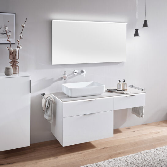 Modernes Badezimmer mit weißem Waschtisch, rechteckigem Spiegel, hohem Schrank, Vase, Pendelleuchten und Holzboden. Minimalistisches Design. Modernes Badezimmer mit weißem Waschtisch, rechteckigem Spiegel, hohem Schrank, Vase, Pendelleuchten und Holzboden. Minimalistisches Design.