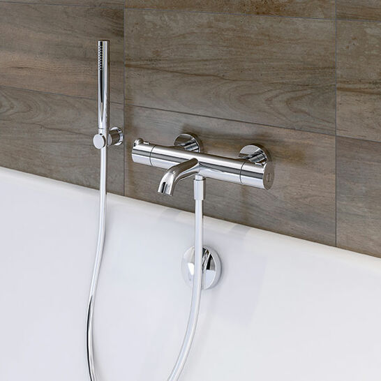 Moderne Badarmatur mit klaren Linien, montiert an einer Wand mit Holzoptik. Elegante Chromoberfläche verleiht der Badewanne einen stilvollen Touch. Moderne Badarmatur mit klaren Linien, montiert an einer Wand mit Holzoptik. Elegante Chromoberfläche verleiht der Badewanne einen stilvollen Touch.