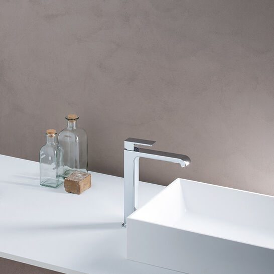 Modernes Waschbecken mit einer eleganten, hohen Chromarmatur. Auf der Ablagefläche stehen Glasflaschen und ein Seifenstück. Schlichtes, minimalistisches Design. Modernes Waschbecken mit einer eleganten, hohen Chromarmatur. Auf der Ablagefläche stehen Glasflaschen und ein Seifenstück. Schlichtes, minimalistisches Design.