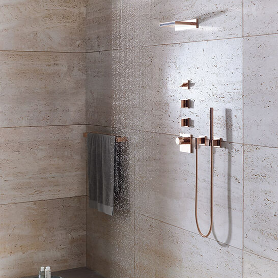 Moderne Dusche mit Regenbrause und roségoldenen Armaturen. Natursteinwände verleihen ein elegantes Ambiente. Handtuchhalter und Ablage für Duschutensilien.