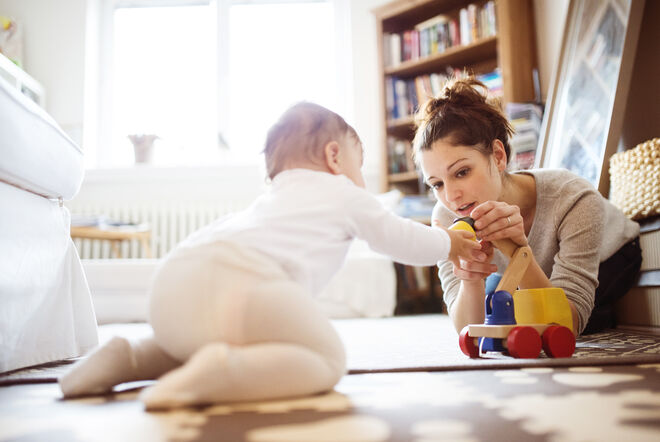 Eine Person spielt mit einem Baby auf dem Boden. Sie sind von Spielzeug umgeben, die Atmosphäre ist warm und gemütlich, perfekt für gemeinsame Momente. Eine Person spielt mit einem Baby auf dem Boden. Sie sind von Spielzeug umgeben, die Atmosphäre ist warm und gemütlich, perfekt für gemeinsame Momente.