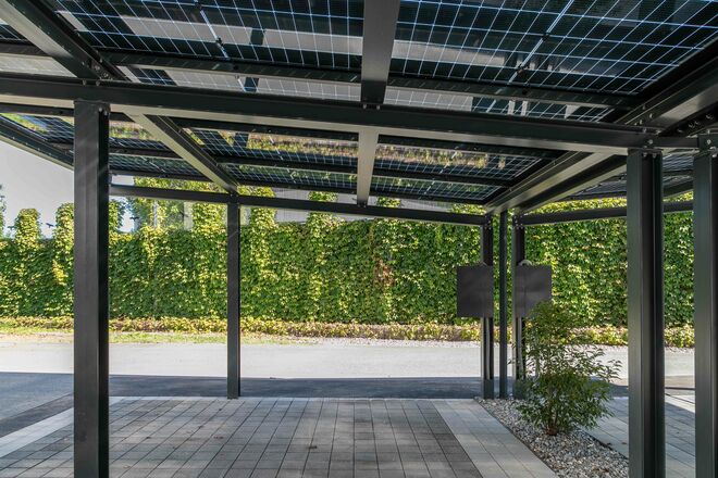 Modernes Carport mit integrierten Solarpanelen, das nachhaltige Energiegewinnung und praktischen Wetterschutz in stilvoller Umgebung vereint.