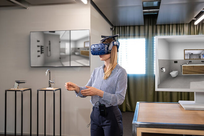 Eine Person mit VR-Brille ist in einem modernen Raum. Auf Bildschirm und Modell sind Badezimmerdesigns zu sehen, was auf VR-gestützte Raumplanung hinweist. Eine Person mit VR-Brille ist in einem modernen Raum. Auf Bildschirm und Modell sind Badezimmerdesigns zu sehen, was auf VR-gestützte Raumplanung hinweist.